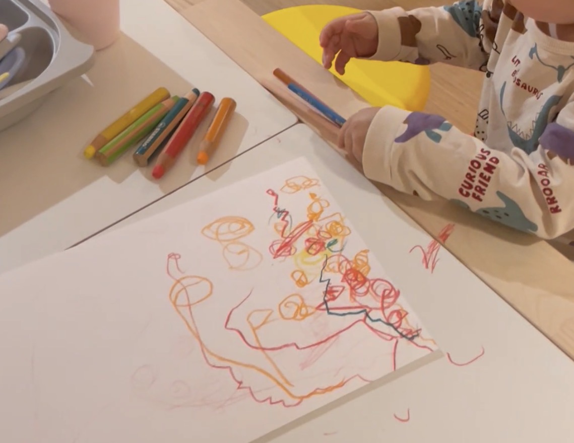 Colorful preschematic drawing with orange and red shapes showing complex compositions and early scene building in child art